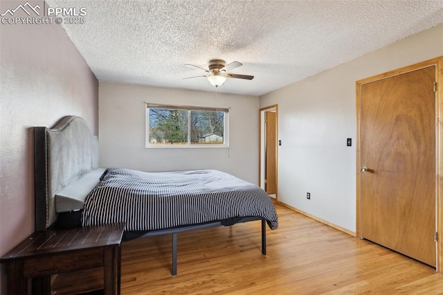 bedroom featuring light wood-style flooring, a textured ceiling, and a ceiling fan