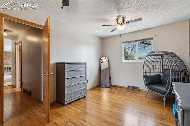 sitting room featuring light wood finished floors, visible vents, and ceiling fan