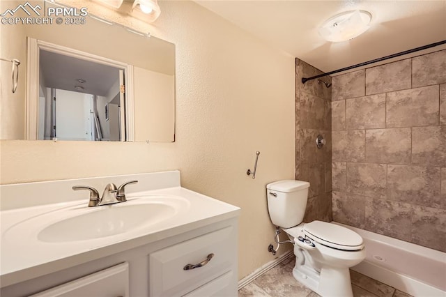 bathroom featuring baseboards, tiled shower, toilet, and vanity
