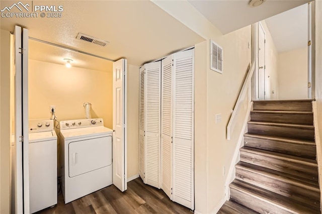 washroom featuring visible vents, washing machine and clothes dryer, laundry area, and dark wood-type flooring