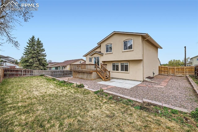 back of house with a patio, a wooden deck, a lawn, stucco siding, and a fenced backyard