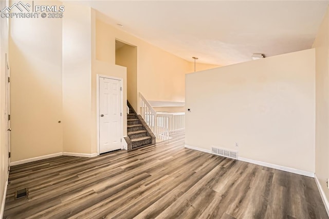 spare room with high vaulted ceiling, stairs, visible vents, baseboards, and wood finished floors
