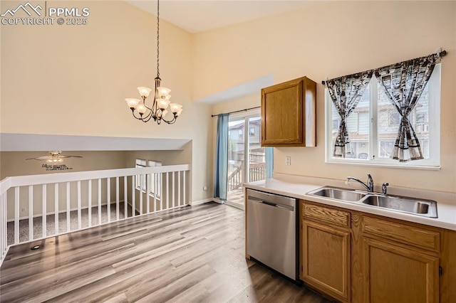 kitchen with a sink, brown cabinetry, decorative light fixtures, stainless steel dishwasher, and wood finished floors
