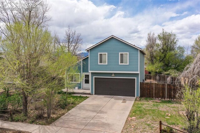 traditional home featuring fence, driveway, and a garage