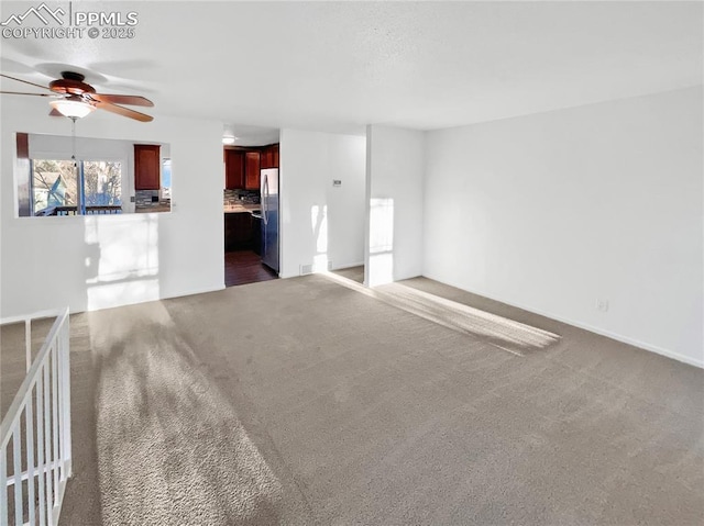 unfurnished living room featuring dark carpet, baseboards, and a ceiling fan