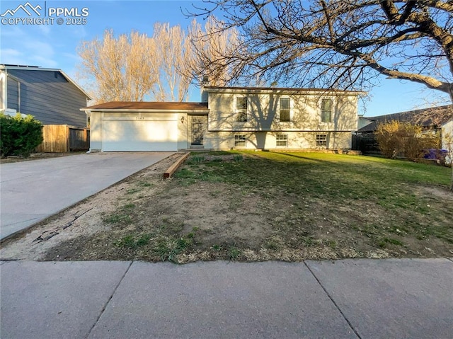 split level home featuring fence, a front lawn, stucco siding, driveway, and a garage