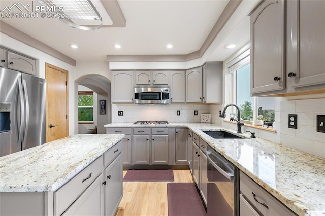 11960 S Conestoga Trl, Elbert, CO 80106 - kitchen with a sink, stainless steel appliances, gray cabinets, arched walkways, and light wood-style flooring