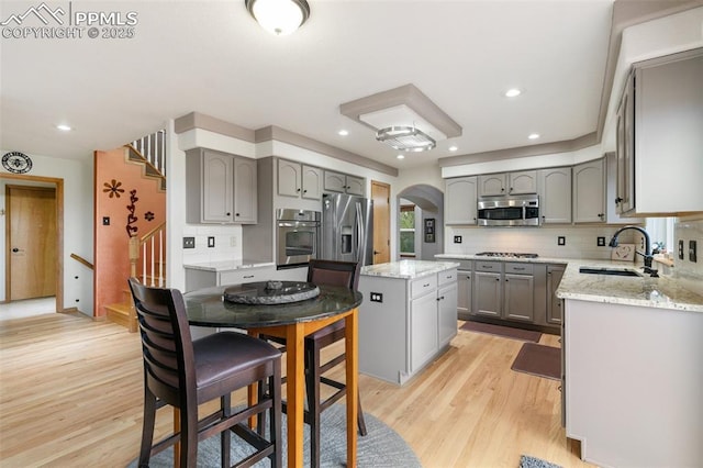 11960 S Conestoga Trl, Elbert, CO 80106 - kitchen featuring gray cabinetry, a sink, stainless steel appliances, arched walkways, and light wood finished floors