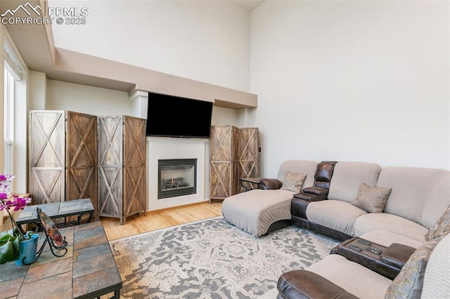 11960 S Conestoga Trl, Elbert, CO 80106 - living area featuring wood finished floors, a glass covered fireplace, and a towering ceiling