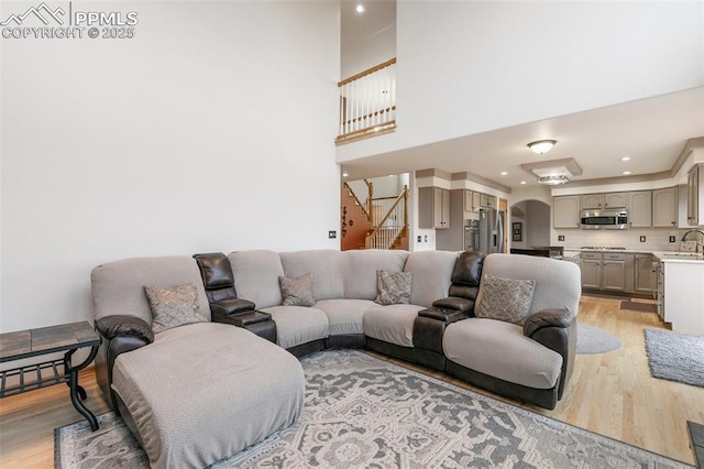 11960 S Conestoga Trl, Elbert, CO 80106 - living area featuring arched walkways, light wood finished floors, stairway, recessed lighting, and a high ceiling