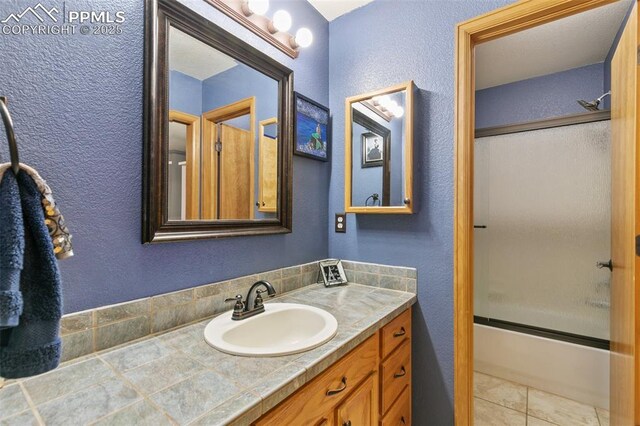 11960 S Conestoga Trl, Elbert, CO 80106 - bathroom with a textured wall, vanity, bath / shower combo with glass door, and tile patterned flooring