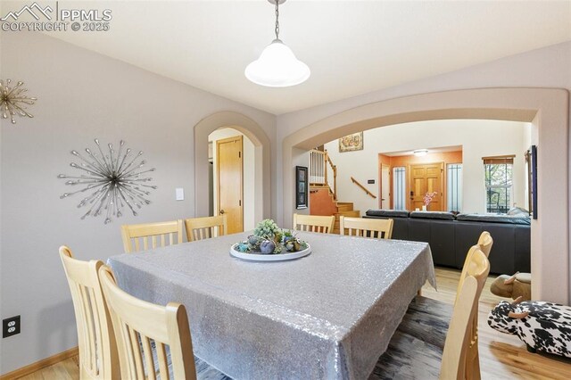 11960 S Conestoga Trl, Elbert, CO 80106 - dining room featuring arched walkways, light wood-style floors, stairs, and baseboards