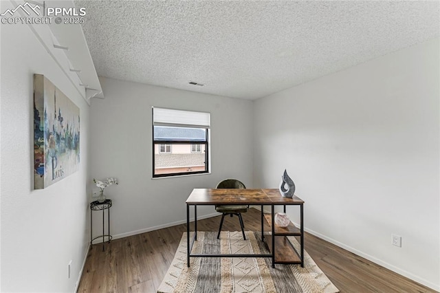 office area with baseboards, wood finished floors, and a textured ceiling