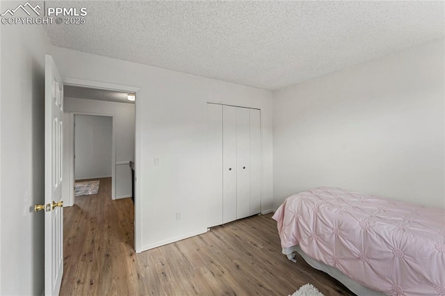 bedroom with baseboards, wood finished floors, a textured ceiling, and a closet