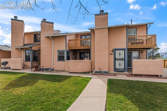 exterior space featuring a yard, a chimney, a balcony, and fence