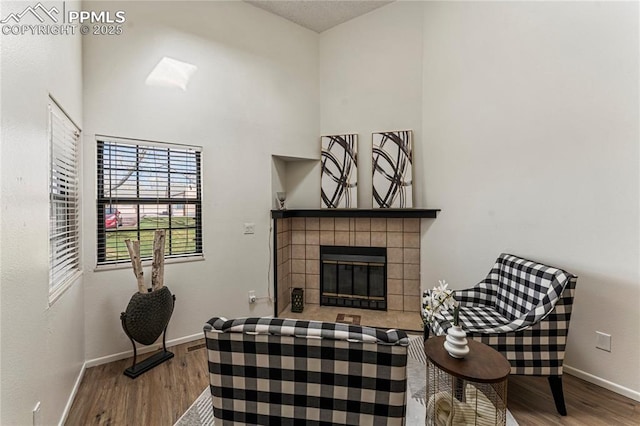 sitting room with baseboards, a tile fireplace, and wood finished floors