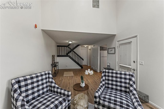 living area featuring stairway, a high ceiling, wood finished floors, and baseboards