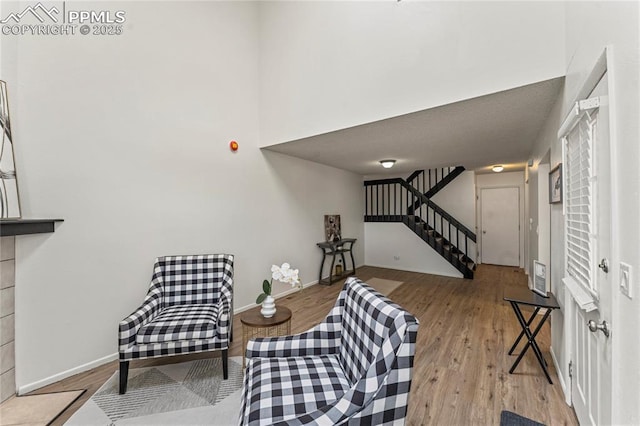 sitting room featuring stairway, baseboards, and wood finished floors