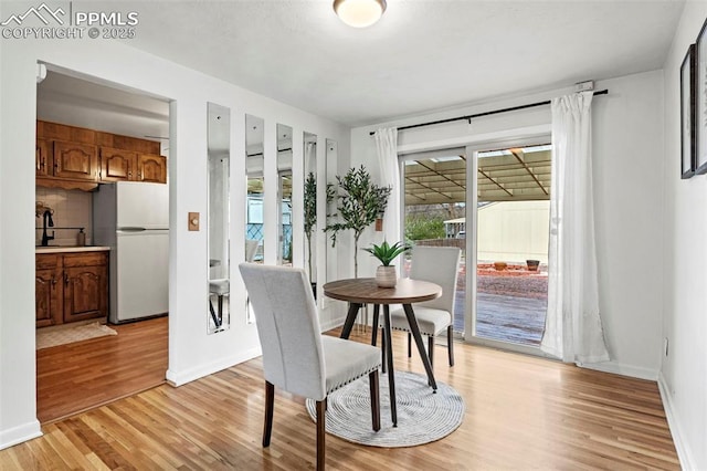 dining area with light wood-style floors and baseboards
