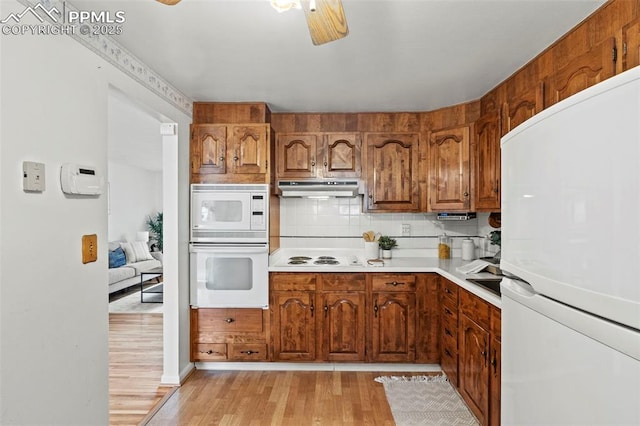 kitchen featuring brown cabinetry, white appliances, light wood-style floors, ceiling fan, and under cabinet range hood