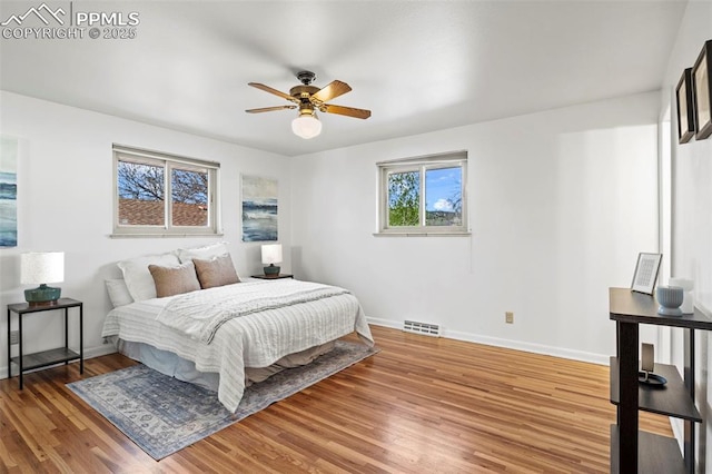 bedroom with baseboards, ceiling fan, light wood-style flooring, and visible vents