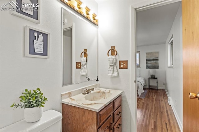 ensuite bathroom featuring toilet, wood finished floors, ensuite bathroom, and vanity