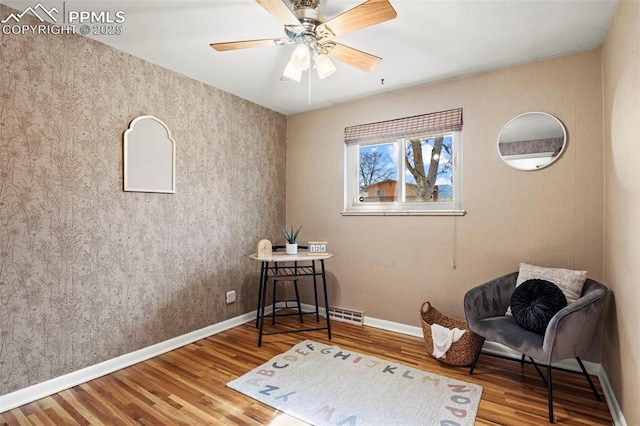 sitting room with baseboards, ceiling fan, visible vents, and wood finished floors
