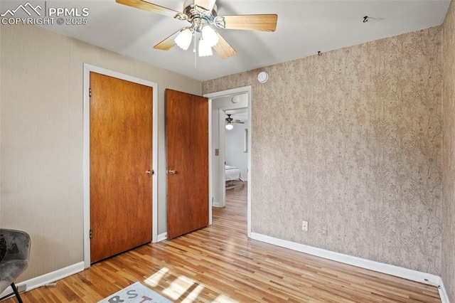unfurnished bedroom with baseboards, ceiling fan, a closet, and wood finished floors