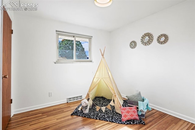 recreation room with baseboards, visible vents, and wood finished floors