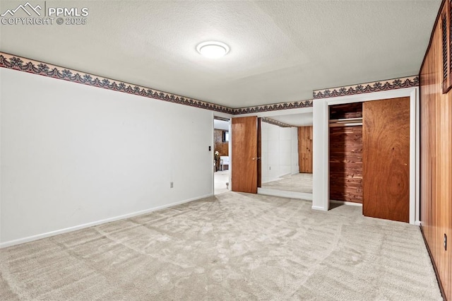 unfurnished bedroom with baseboards, a textured ceiling, carpet, and two closets