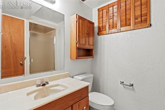 bathroom featuring vanity, a textured wall, toilet, and a shower
