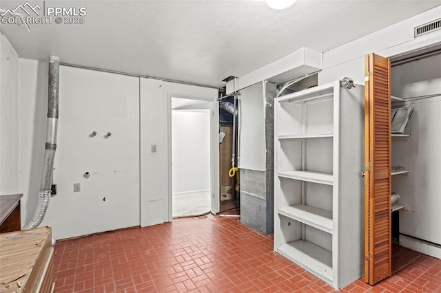 interior space with brick patterned floor, visible vents, and a closet