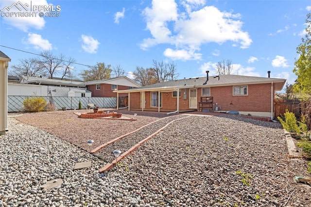back of property with brick siding, a fenced backyard, and a patio area
