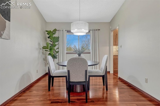 dining area with baseboards and wood finished floors