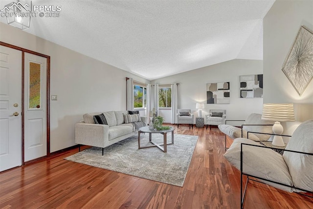 living area with vaulted ceiling, wood finished floors, and a textured ceiling