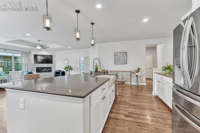 4464 Portillo Pl, Colorado Springs, CO 80924 - kitchen featuring wood finished floors, freestanding refrigerator, ceiling fan, a fireplace, and a sink