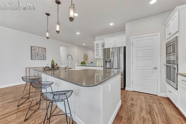 4464 Portillo Pl, Colorado Springs, CO 80924 - kitchen featuring white cabinetry, a sink, appliances with stainless steel finishes, dark countertops, and light wood finished floors