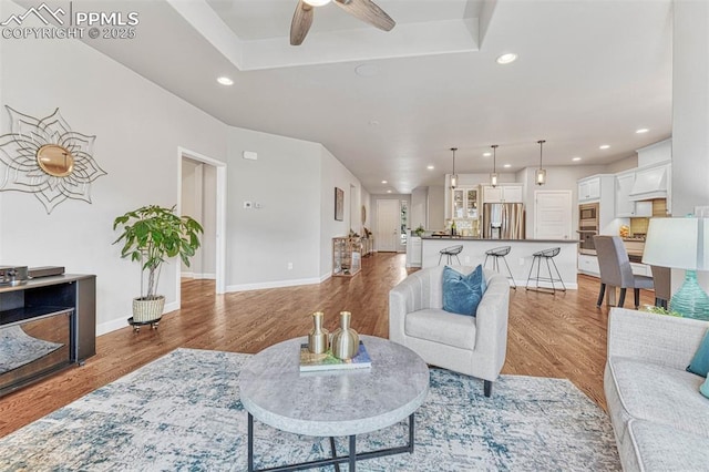 4464 Portillo Pl, Colorado Springs, CO 80924 - living room featuring recessed lighting, light wood-style floors, a tray ceiling, a ceiling fan, and baseboards