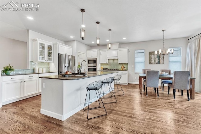 4464 Portillo Pl, Colorado Springs, CO 80924 - kitchen featuring white cabinetry, tasteful backsplash, dark countertops, stainless steel appliances, and wood finished floors