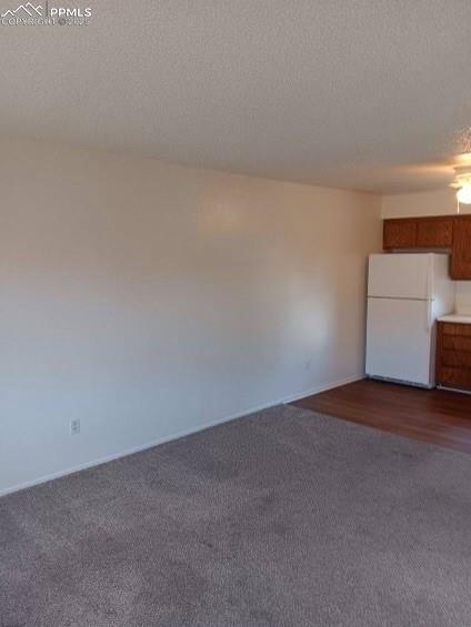 720 E Hills Rd, Colorado Springs, CO 80909 - spare room with dark colored carpet, a textured ceiling, and baseboards