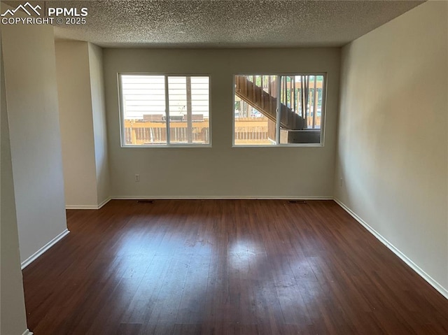 720 E Hills Rd, Colorado Springs, CO 80909 - spare room featuring dark wood-type flooring, a textured ceiling, and baseboards