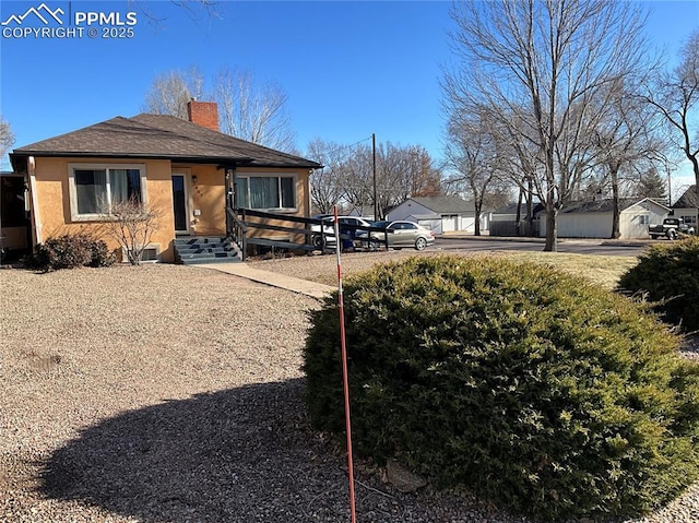 1007 Iowa Ave, Colorado Springs, CO 80909 - view of home's exterior with concrete driveway, a chimney, and stucco siding