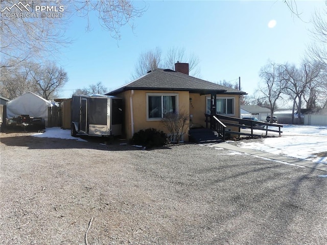 1007 Iowa Ave, Colorado Springs, CO 80909 - exterior space with a shingled roof, a chimney, and stucco siding