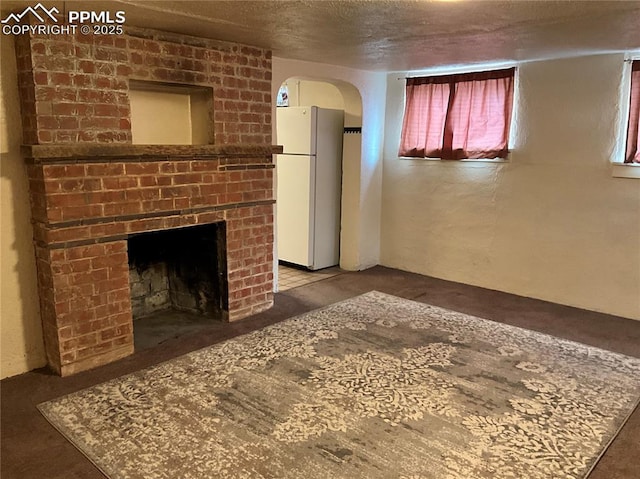 1007 Iowa Ave, Colorado Springs, CO 80909 - unfurnished living room featuring a brick fireplace, arched walkways, and a textured ceiling