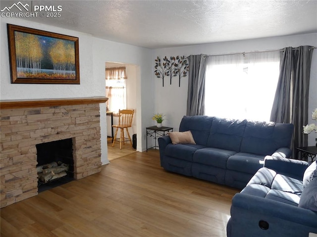 1007 Iowa Ave, Colorado Springs, CO 80909 - living area with wood finished floors, a fireplace, and a textured ceiling