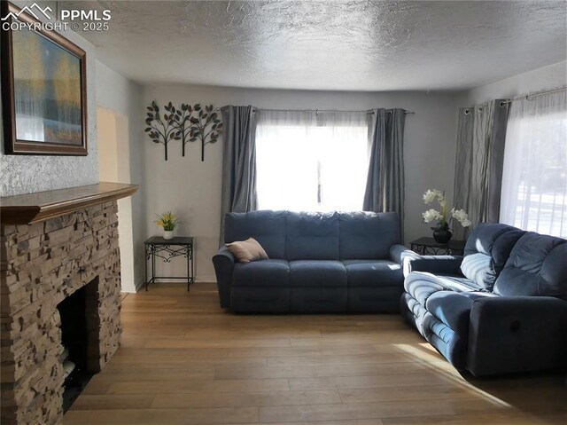 1007 Iowa Ave, Colorado Springs, CO 80909 - living room featuring a wealth of natural light, wood finished floors, a textured ceiling, and a fireplace
