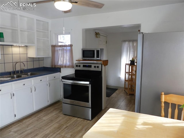 1007 Iowa Ave, Colorado Springs, CO 80909 - kitchen featuring white cabinets, stainless steel appliances, a sink, dark countertops, and open shelves