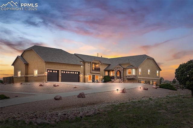 french country style house with a garage, concrete driveway, fence, and stucco siding