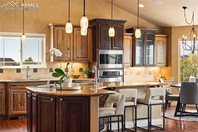 kitchen with a sink, stainless steel appliances, a kitchen island with sink, lofted ceiling, and tasteful backsplash