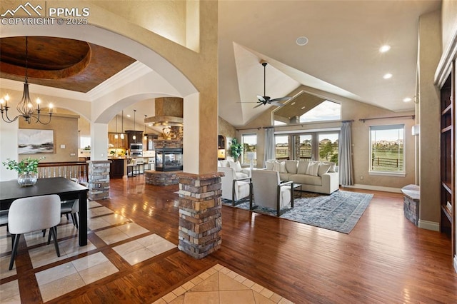 living room with ceiling fan, a chandelier, arched walkways, high vaulted ceiling, and inlaid floor details